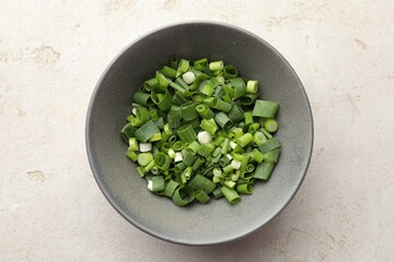 Bowl with cut green onions on light grey table, top view