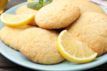 Tasty lemon cookies and fruit slices on black wooden table, closeup