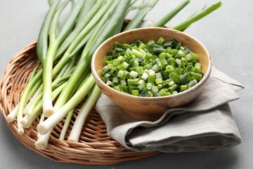 Whole and cut fresh green onions on grey table, closeup