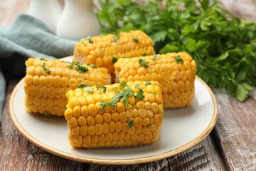 Pieces of boiled corncobs with parsley on wooden table, closeup