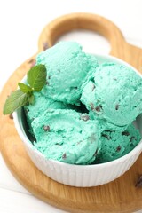 Tasty mint chocolate chip ice cream on white wooden table, closeup