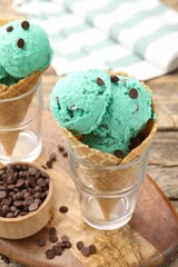 Tasty mint chocolate chip ice cream in waffle cones on wooden table, closeup