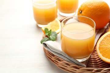 Fresh orange juice, mint and fruits on light wooden table, closeup. Space for text