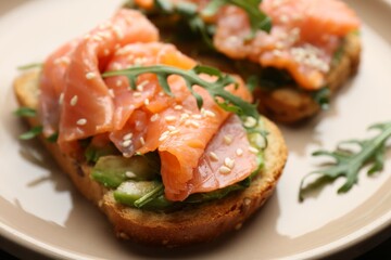 Tasty bruschetta with salmon, avocado, arugula and sesame seeds on table, closeup