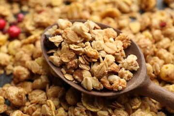Tasty granola with dried fruits and spoon on table, closeup