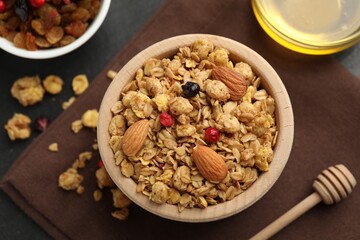 Tasty granola with dried fruits, nuts and honey on black table, flat lay