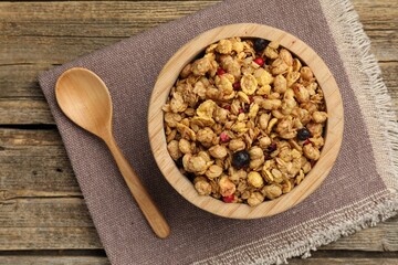Tasty granola with dried fruits in bowl on wooden table, top view