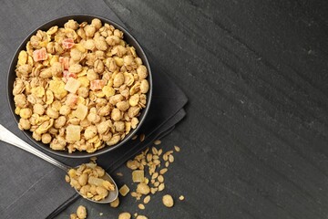 Tasty granola with dried fruits in bowl on black table, flat lay. Space for text
