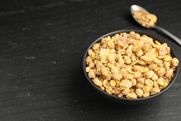 Tasty granola with dried fruits in bowl on black table, closeup. Space for text