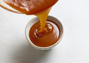 freshly cooked caramel sauce pouring in bowl