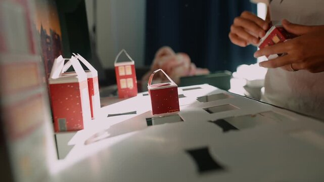 Focused student arranges small houses with exactness during bright light