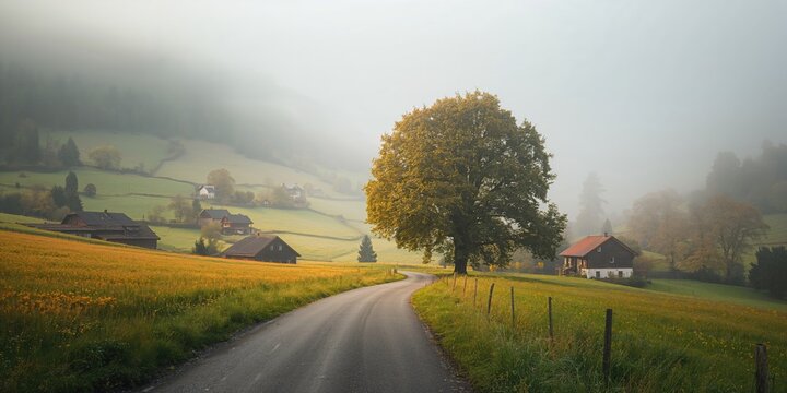 Scenic rural landscape with winding road, trees, and a small village in a foggy morning setting, seasonal change