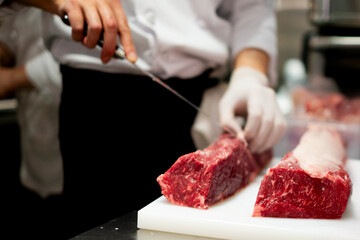 Obraz premium 肉の塊を切るシェフ