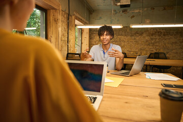 Red-haired woman in yellow shirt observing colleague from a distance