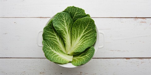 Fresh Chinese cabbage leaves in a colander on a white wooden surface, suitable for food preparation or washing, neutral background