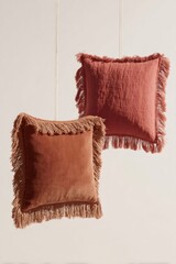 Bohemian terracotta and rust colored pillows featuring fringes, floating in air, representing comfort and home decor