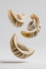 Frozen dumplings floating against a white background, uncooked gyoza ready for cooking, asian food preparation