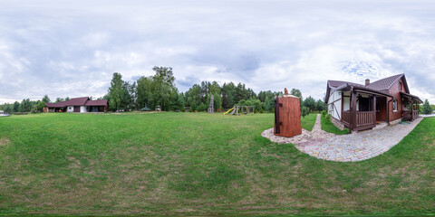 Seamless spherical HDRI panorama with a 360-degree angle view of a green lawn and a house in the background. Green lawn, green paddock. VR content.