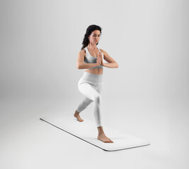 Mockup of white floor mat for yoga, trainer in asana, dressed in training suit, isolated on background.