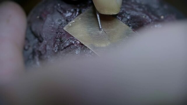 Hand engraving elegant cursive script letters into gold jewelry pendant closeup macro detail