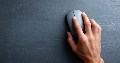 Close-up of a human hand using a modern wireless computer mouse on a dark textured surface with natural lighting and shadow