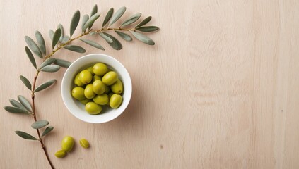 Olive oil and olive branch with fresh green olives in a white porcelain bowl, highlighting plant-based ingredients
