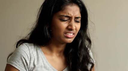 Young woman from Asian descent suffers severe migraine and displays visible distress