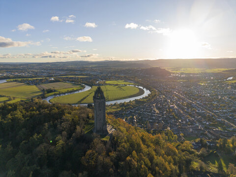 Aerial view of the National Wallace Monument standing tall amidst autumn foliage, the River Forth snaking through the landscape, Stirling, Scotland, United Kingdom.