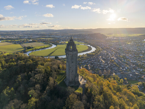 Aerial view of the imposing Wallace Monument atop Abbey Craig, overlooking the winding River Forth and the sprawling cityscape, Stirling, Scotland, United Kingdom.