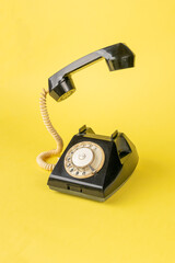 Vintage Rotary Telephone on Bright Yellow Background