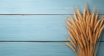 Fototapeta premium Ears of wheat arranged on a rustic blue wooden surface, suitable as a background for text or design elements