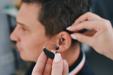 Man trying modern compact hearing aids. Closeup of patient ear. Hearing rehabilitation clinic selecting digital device for middle age deaf people. Close-up