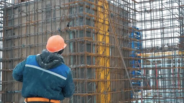 Building construction, monolithic works, reinforcement. two construction workers with their backs to the camera.
