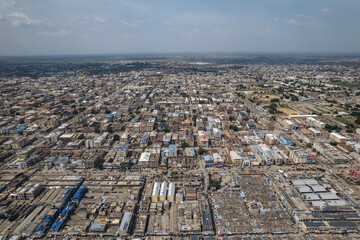 Aerial view of a sprawling cityscape with tightly packed buildings and industrial zones under a vast sky, Kano, Kano, Nigeria.