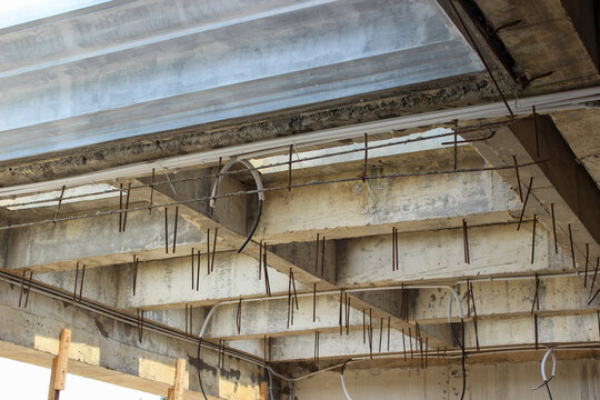 Unfinished concrete building roof structure with protruding steel reinforcements, partially covered by metal sheeting, on a construction site.