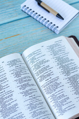 Open holy bible book with notebook and pen on wooden table. Christian study and reading, biblical concept.