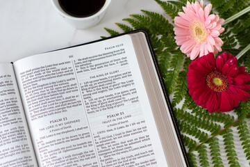 Open holy bible book with flowers and coffee cup. Christian study, spiritual growth, biblical concept.