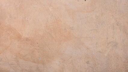 Rough and uneven old peach-painted stucco wall surface with minor stains and uneven brush marks. The color varies from light orange to beige tones.