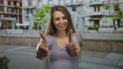 Young woman in a purple shirt showing a thumbs up gesture on a city street with colorful buildings...
