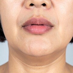Fototapeta premium A close-up view presents the lower face. The lips are visible, skin tone is uneven, showing aging, texture, some shadow