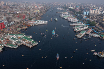 Aerial view of the bustling waterway, alive with ferries and boats creating foamy wakes, cutting through the heart of the city, Dhaka, Dhaka Division, Bangladesh.