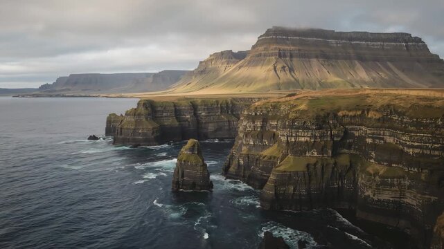 Drone flying along rugged sea cliffs and ocean stack at golden hour