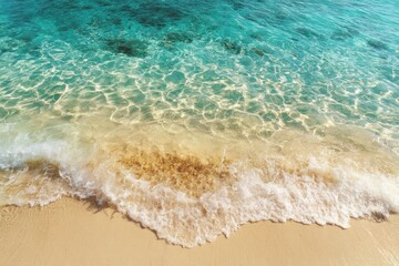 Clear ocean water laps against the shore, creating gentle waves on the sandy beach under bright sunlight