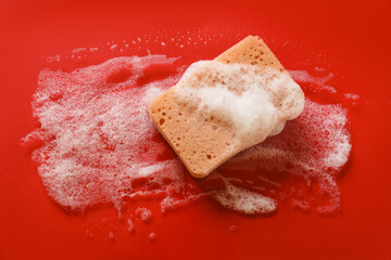 Kitchen sponge with foam on red background, top view. Space for text