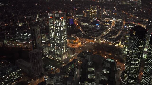Night aerial view of Frankfurt skyline with illuminated skyscrapers like Opernturm UBS tower. Financial district cityscape showing modern architecture and urban lights
