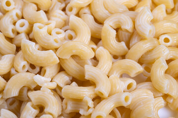 Macaroni storage overview, Uncooked pasta stockpile description, Industrialscale macaroni stacking and presentation, Arranged uncooked elbow macaroni in textured matte display