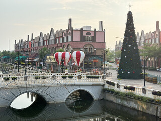 A charming European-style waterfront town square, decorated for the holiday season or a festive event, capturing a blend of architecture and leisure.