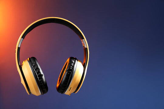 Pair of stylish headphones in air on color gradient background, space for text - Powered by Adobe