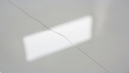 Delicate hair strand resting on pristine white surface, highlighting texture and natural form. Single hair strand detail reveals thinness and dark color against bright background.