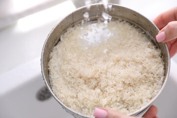Woman washing rice in sieve at sink, closeup